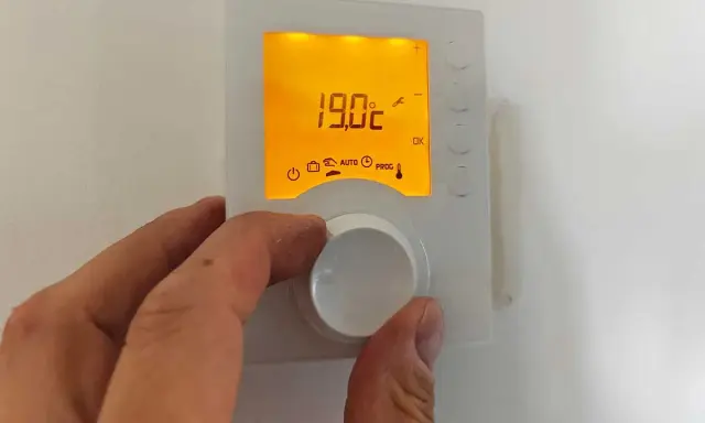Main tenant ajuste la hauteur du thermostat pour optimiser le confort. L'écran affiche 19.0°C.