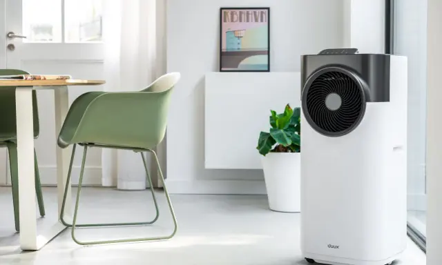 Le climatiseur pure blizzard, blanc et gris, trône dans un salon moderne aux côtés d'une plante verte et d'un tableau.