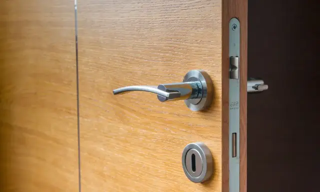 Porte isolante thermique entre garage et maison, en bois clair avec poignée chromée.