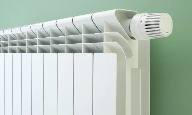Radiateur blanc moderne avec thermostat. Le fluide caloporteur circule pour chauffer la pièce.
