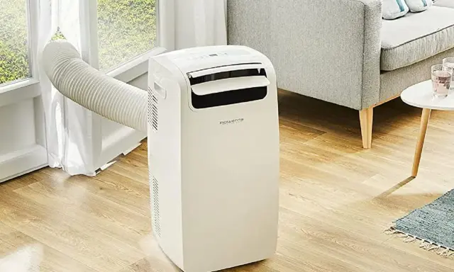 Climatiseur mobile Rowenta, la meilleur marque climatiseur mobile pour un confort optimal. Un appareil blanc avec un tuyau d'évacuation vers la fenêtre.