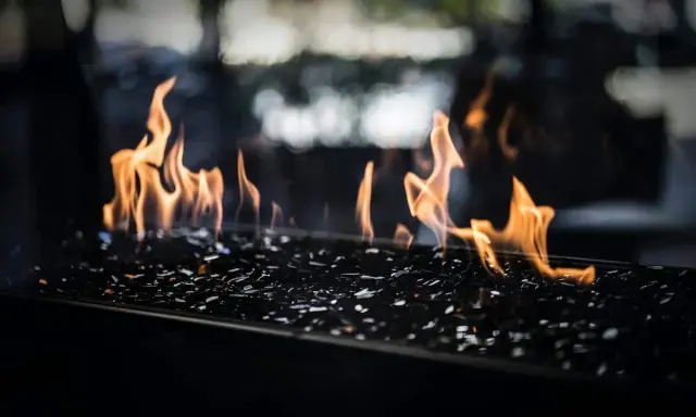 Flammes dansant sur des éclats de verre noir, évoquant le chauffage au pétrole, ses avantages et inconvénients.