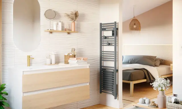 Salle de bain moderne avec meuble vasque, miroir ovale et sèche-serviettes gris. La puissance du sèche serviette assure des serviettes chaudes.