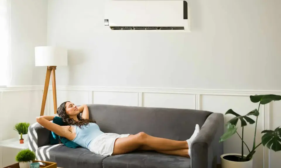 Une femme se détend sur un canapé sous un climatiseur, profitant de la puissance clim pour 40m2.