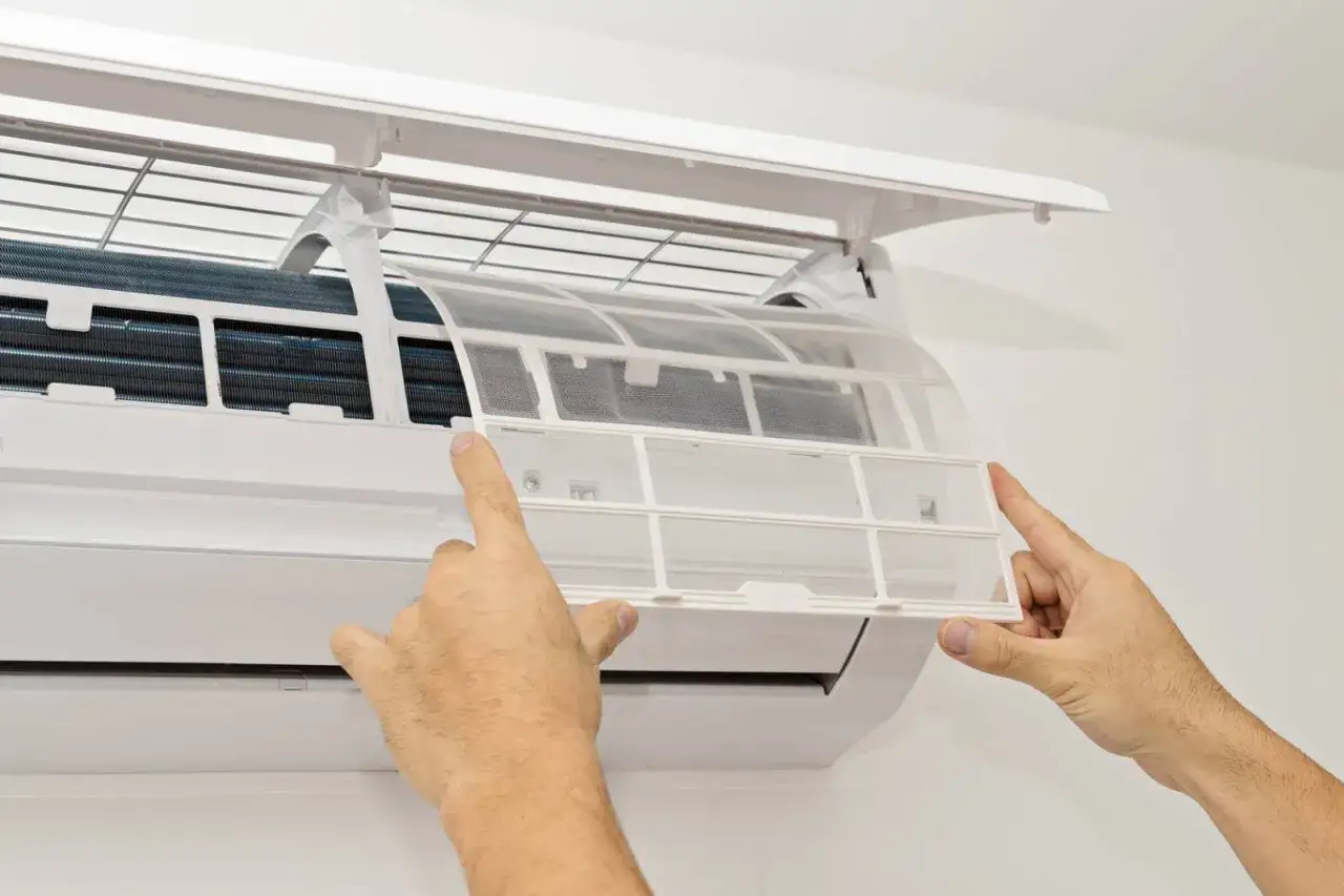 Maintenant, d&eacute;couvrez comment nettoyer une clim : une personne retire le filtre &agrave; air d'une unit&eacute; int&eacute;rieure de climatisation.