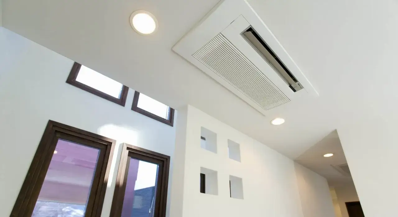 Un syst&egrave;me de climatisation gainable plafond discret, int&eacute;gr&eacute; dans un plafond blanc, assure le confort d'une pi&egrave;ce moderne avec ses fen&ecirc;tres et ses niches murales.