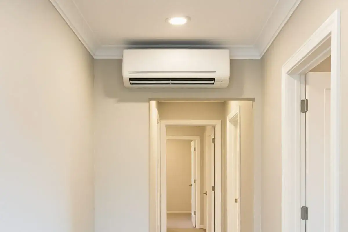 Clim dans couloir pour refroidir les chambres. L'appareil est fix&eacute; au mur, au-dessus de plusieurs portes ouvertes menant &agrave; d'autres pi&egrave;ces.