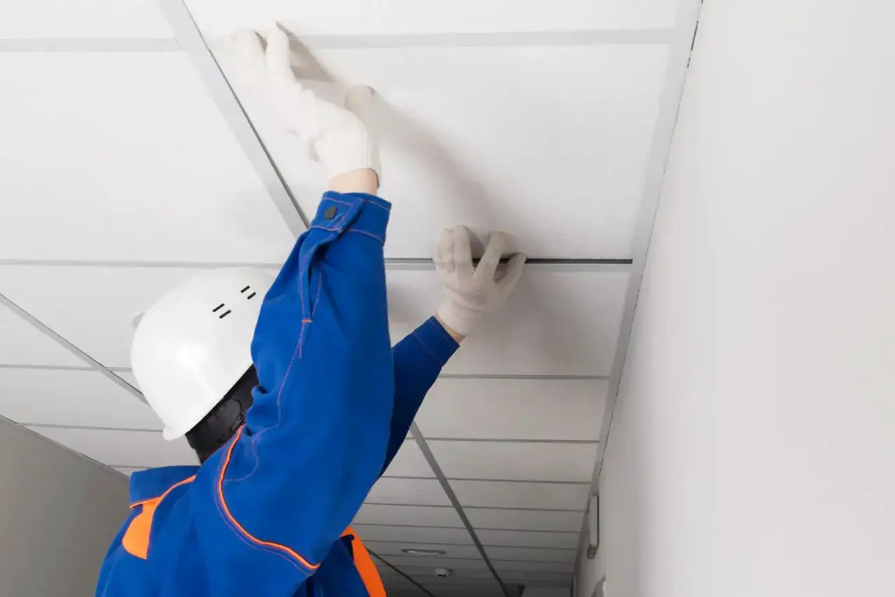 Un ouvrier installe un faux plafond dans un garage, améliorant l'isolation.