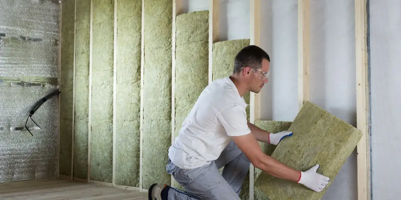 Un ouvrier installe des panneaux isolants pour le cout isolation interieur d'un b&acirc;timent.