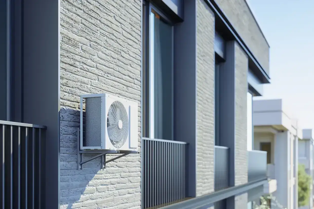 Unit&eacute; ext&eacute;rieure de climatisation r&eacute;versible fix&eacute;e sur un mur de briques. L'image sugg&egrave;re des inconv&eacute;nients potentiels comme le bruit ou l'esth&eacute;tique.