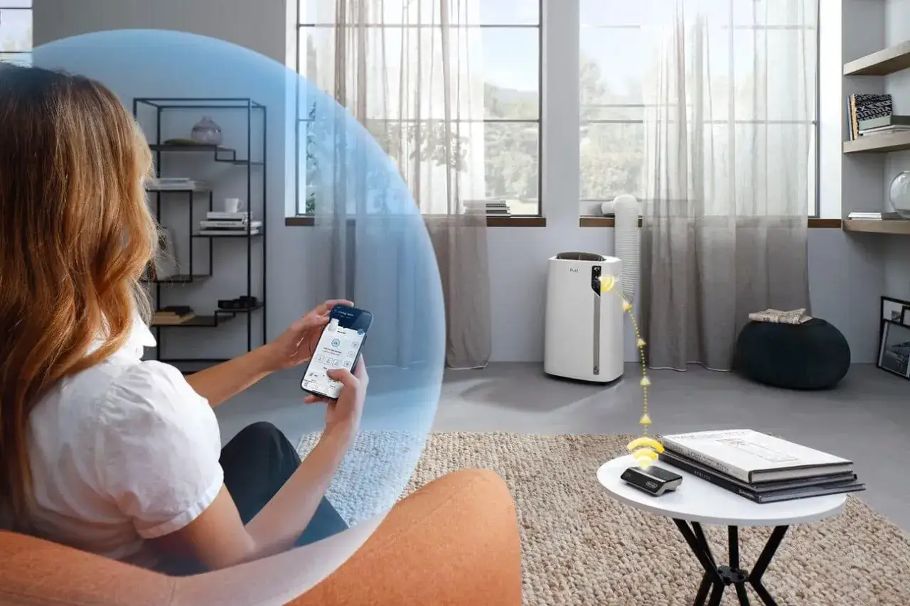 Une femme contr&ocirc;le &agrave; distance son climatiseur Delonghi PAC EL112 CST WiFi via son smartphone, pour un confort optimal.