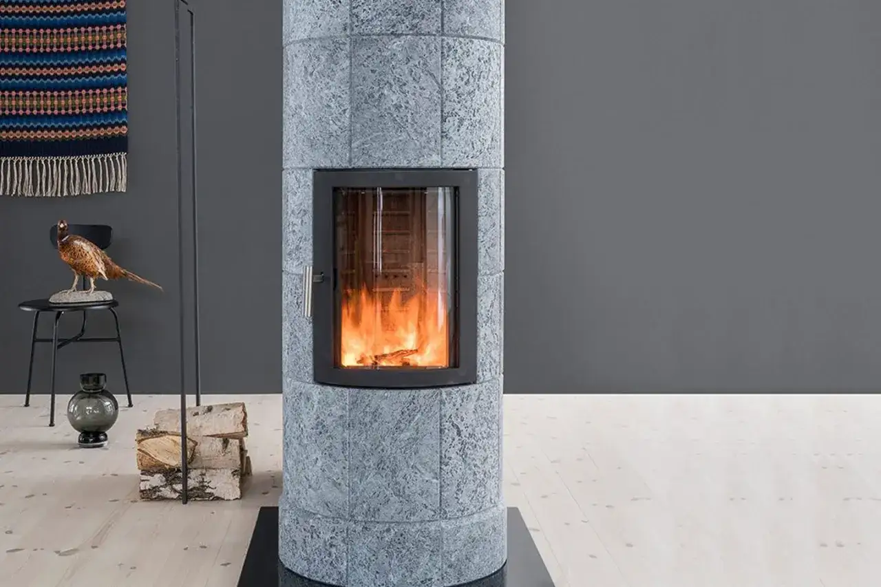 Po&ecirc;le cylindrique en pierre st&eacute;atite pour un chauffage doux et durable. Flammes vives dans la vitre.
