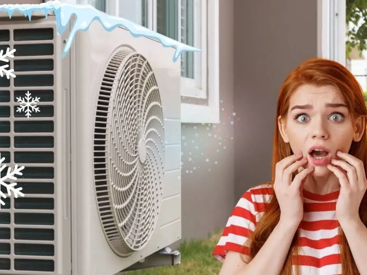 Une jeune femme paniqu&eacute;e d&eacute;couvre une panne de climatisation avec des gla&ccedil;ons et des flocons de neige sur l'unit&eacute; ext&eacute;rieure.