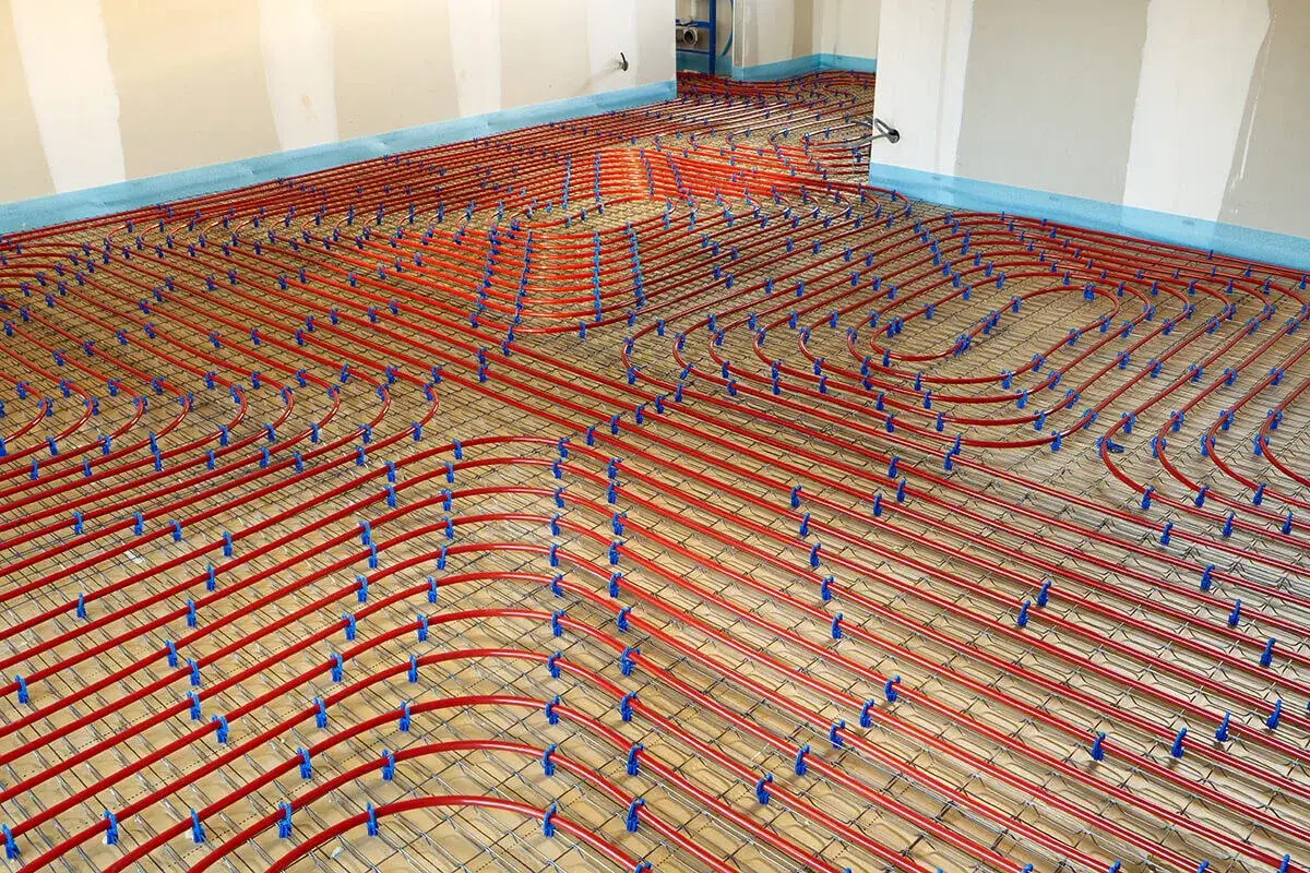 Installation de tubes rouges pour un chauffage au sol, une alternative moderne au radiateur traditionnel.