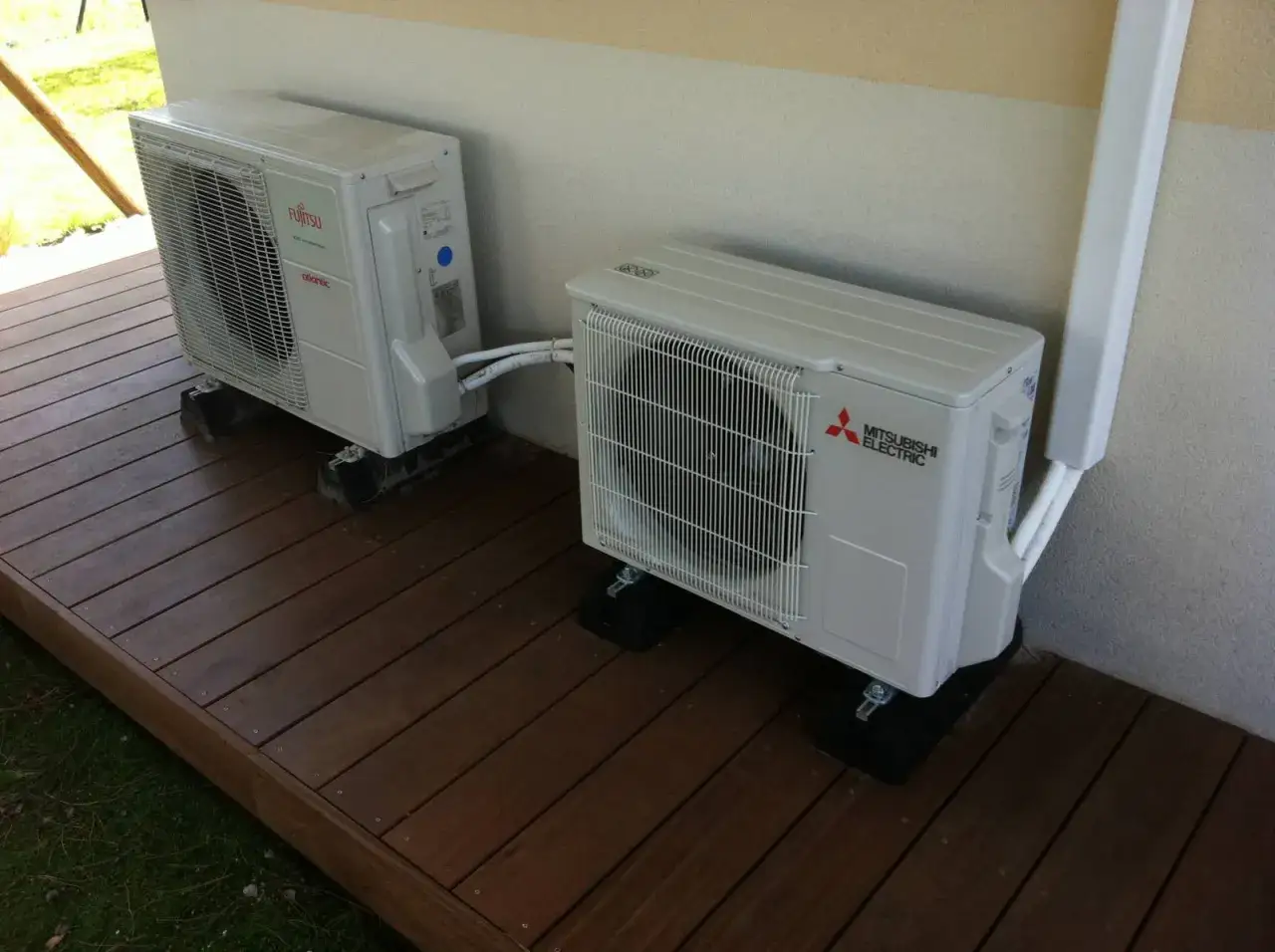 Deux unit&eacute;s ext&eacute;rieures de climatisation, dont une Mitsubishi Heavy Industries, sont install&eacute;es sur une terrasse en bois.