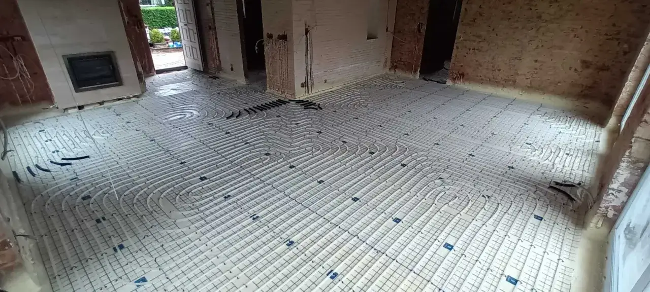 Installation d'un plancher chauffant avant le désembouage. Les tuyaux sont posés en spirale sur une grille.