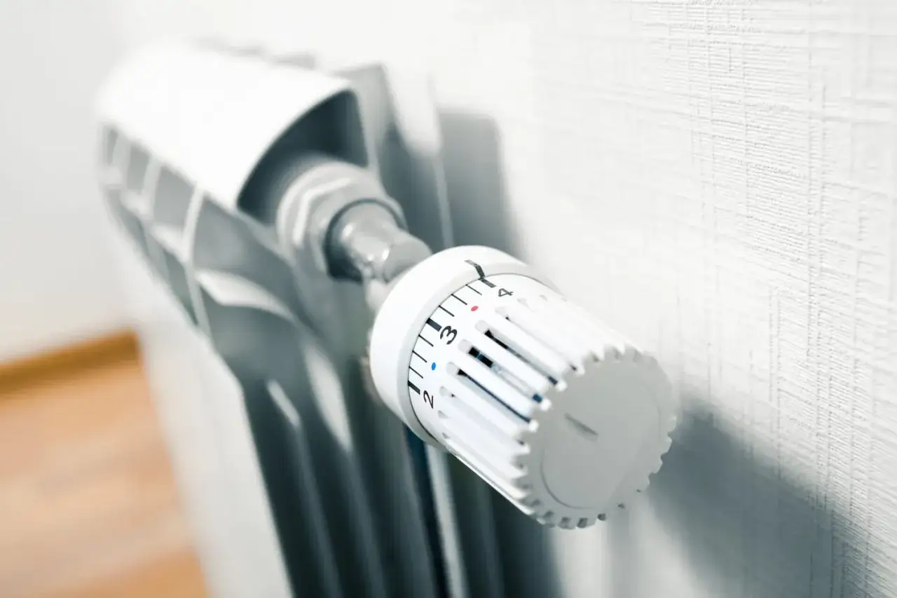 Thermostat blanc sur un radiateur, réglant la température du système de chauffage maison.