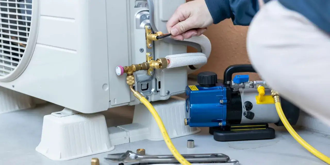 Technicien connectant une pompe de relevage &agrave; un climatiseur. L'entretien r&eacute;gulier optimise la dur&eacute;e de vie pompe de relevage climatisation.