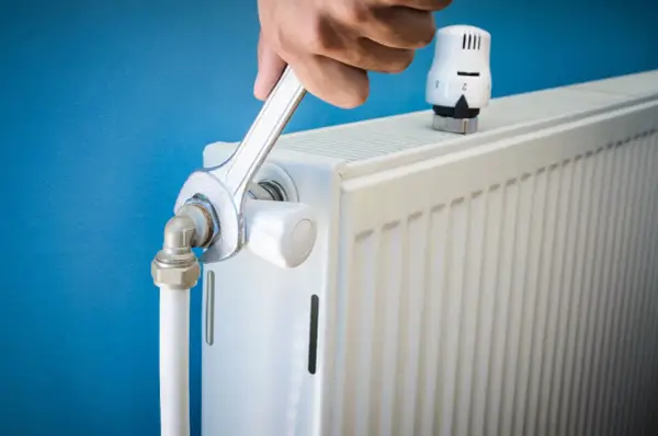 Main tenant resserre une connexion sur un radiateur qui fait du bruit.