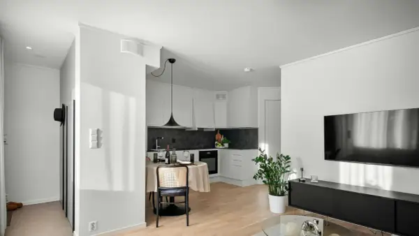 Un studio moderne avec cuisine, coin repas et salon. Un climatiseur discret est installé au plafond, assurant le confort.