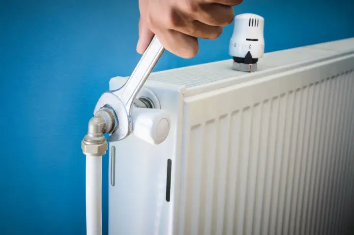 Main tenant resserre une connexion sur un radiateur qui fait du bruit.