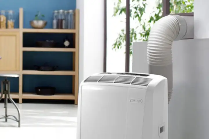 Climatiseur mobile blanc avec tuyau d'évacuation relié à une fenêtre.