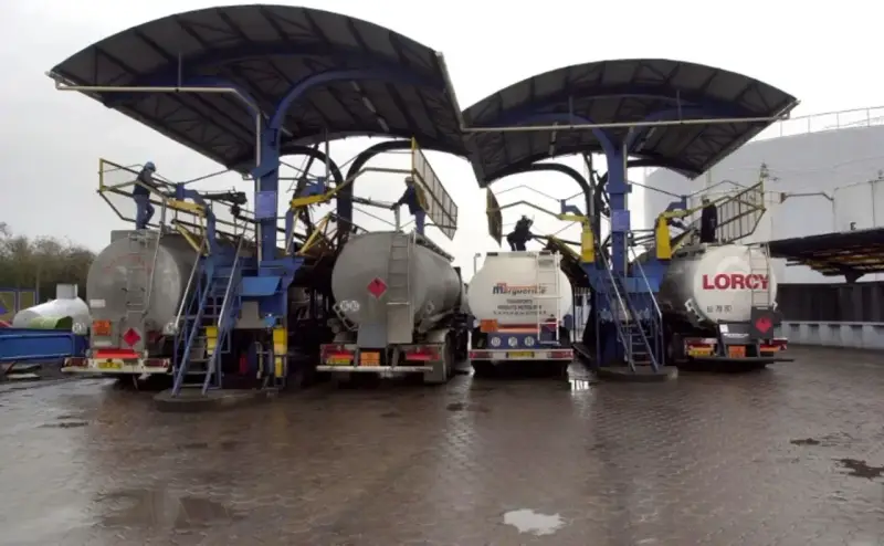 Camions citernes en cours de chargement sous des auvents. Le chauffage fioul prix est une préoccupation majeure pour les ménages.